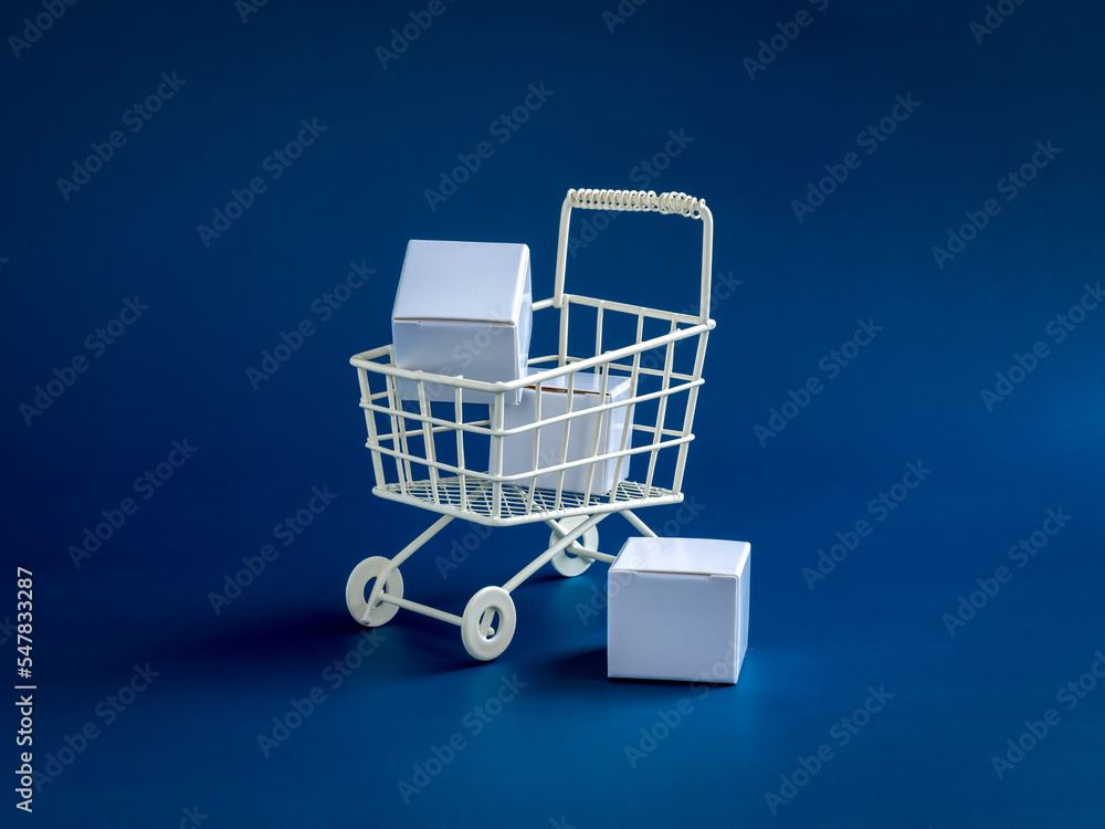 Shopping online business, e-commerce, delivery, purchasing power concepts. White parcel boxes in shopping trolley cart supermarket isolated on blue background, minimal style.