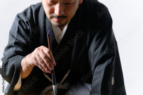Japanese man who looks like a calligrapher(shodo) doing calligraphy photo