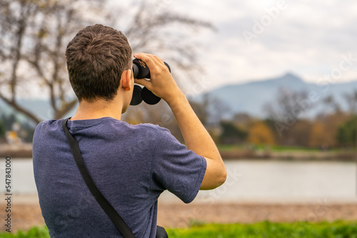 A man looking through binoculars at mountains. Travel concept. 