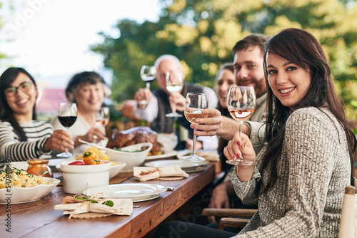 Family  portrait and wine toast  food and thanksgiving meal on patio by happy  smile and relax people. Happy family  cheers and buffet lunch celebration of tradition  holiday and social gathering