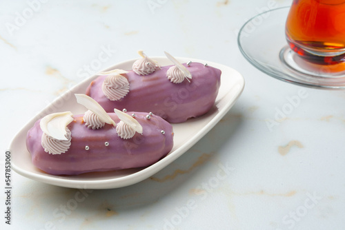 Two eclair cakes with violet frosting on white plate