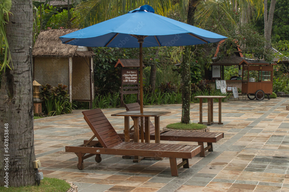 vacation by the pool with wooden chairs and umbrellas
