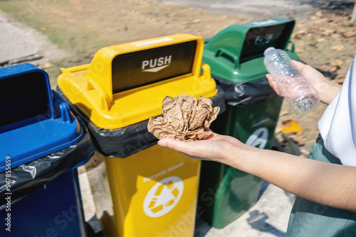 Woman hand throwing garbage plastic bottle and crumpled paper into rubbish bin. Waste separation and recycling concept © Ton Photographer4289
