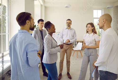 Group of scientists from different countries communicate during break in scientific symposium with supervisor. African American woman convinces colleagues of correctness of scientific conclusions. photo