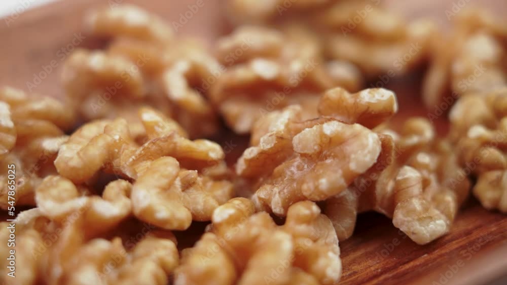Peeled walnut cores sliding on a rustic brown wooden bowl. Dry nuts kernels. Macro. Slow motion Peeled walnut cores sliding on a rustic brown wooden bowl. Dry nuts kernels. Macro. Slow motion