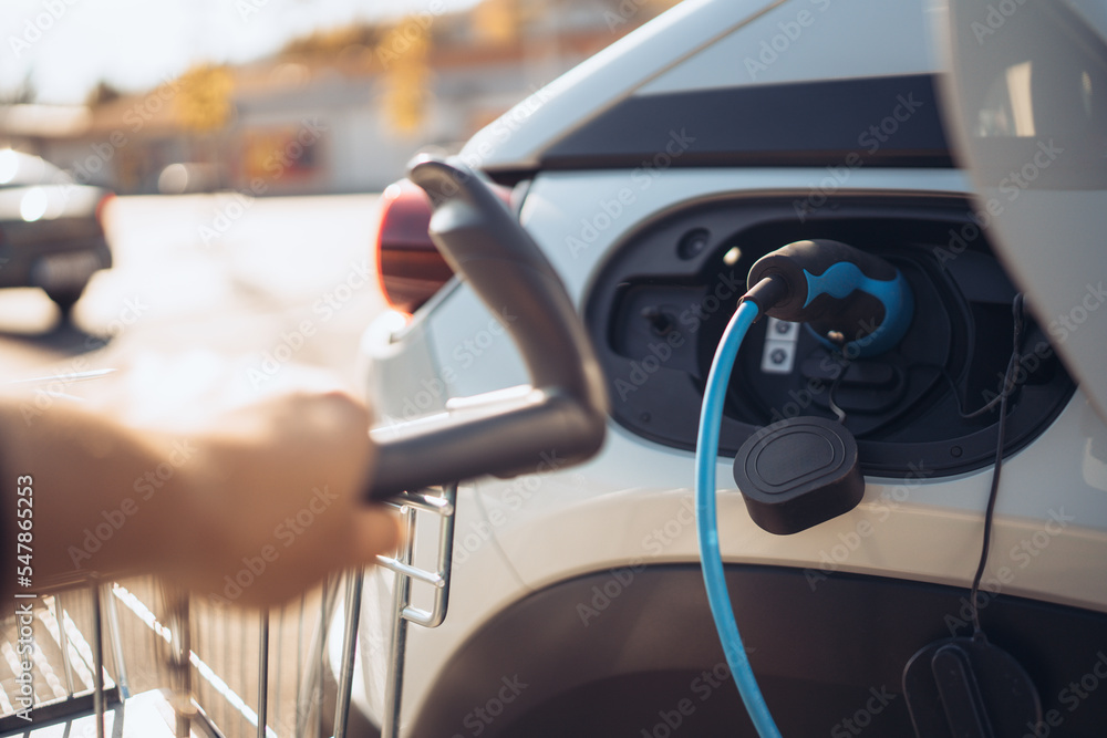 Close-up of charging electric car at supermarket parking. Close-up of charging electric car at supermarket parking.