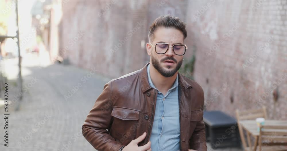 project video of sexy stylish bearded man outside in an old city walking and looking around, adjusting jacket and glasses project video of sexy stylish bearded man outside in an old city walking and looking around, adjusting jacket and glasses
