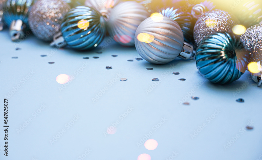 Fototapeta premium Christmas baubles on blue background. Frame border. Christmas New Year composition background blue grey silver colored. Christmas lights. Minimal concept.