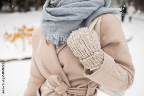 A girl holds a white backpack with mittens in winter under the snow