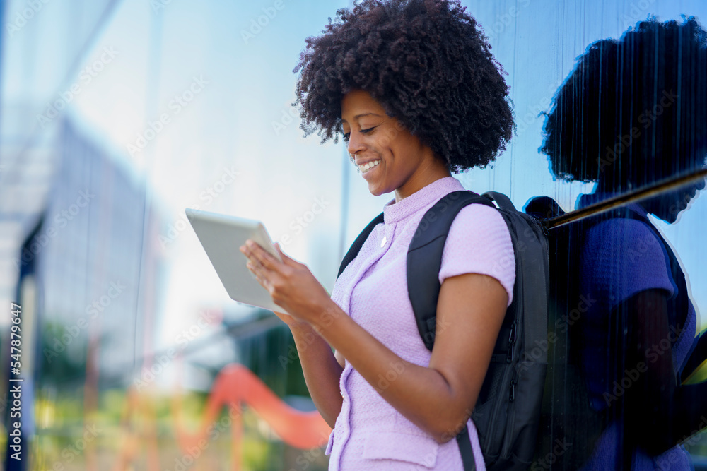 Happy businesswoman using tablet PC standing by wall Happy businesswoman using tablet PC standing by wall