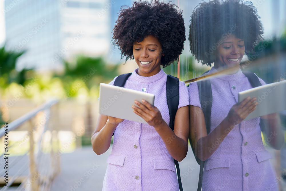 Happy businesswoman using tablet PC leaning on wall Happy businesswoman using tablet PC leaning on wall