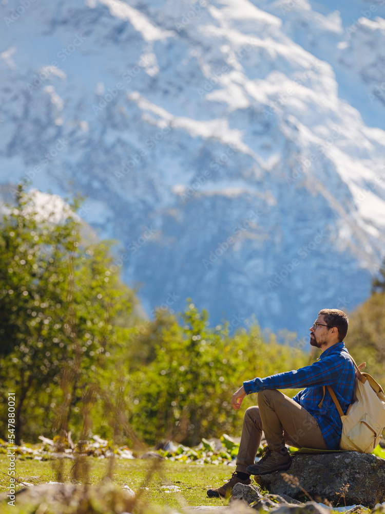 journey by Irkis valley, Arkhyz, Karachay-Cherkessia, North Caucasus. Man hiking up mountain in snowy mountain valley with blue sky and clouds and beautiful forest near river Psysh, Caucasus. journey by Irkis valley, Arkhyz, Karachay-Cherkessia, North Caucasus. Man hiking up mountain in snowy mountain valley with blue sky and clouds and beautiful forest near river Psysh, Caucasus.