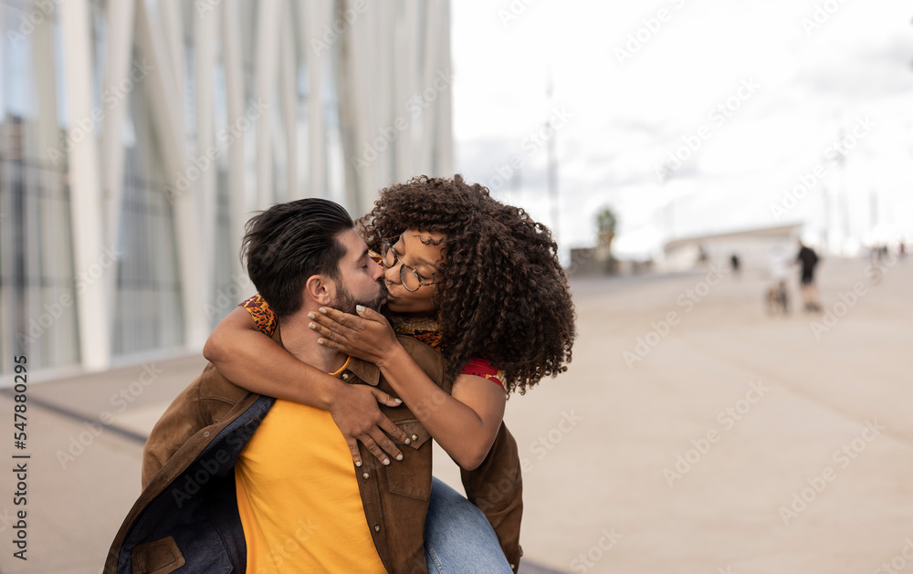 Young boyfriend piggybacking and kissing girlfriend at footpath Young boyfriend piggybacking and kissing girlfriend at footpath