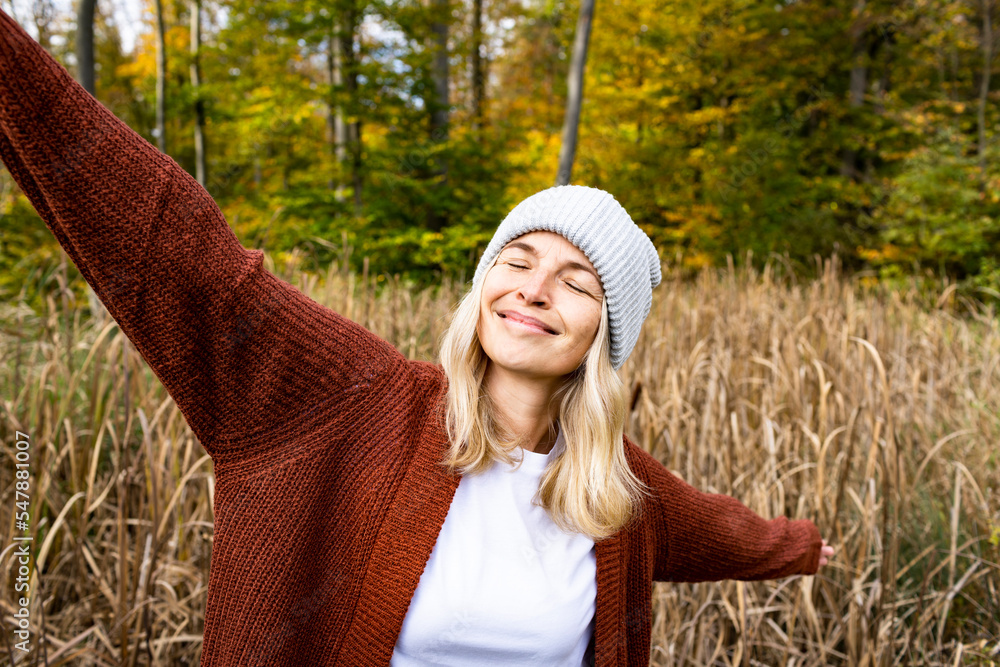 © Westend61 - Smiling mature woman with eyes closed and arms outstretched in meadow