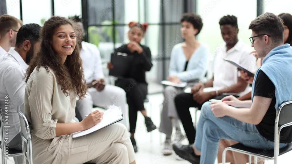 businesswoman with paper folder sitting near multiethnic colleagues during seminar businesswoman with paper folder sitting near multiethnic colleagues during seminar