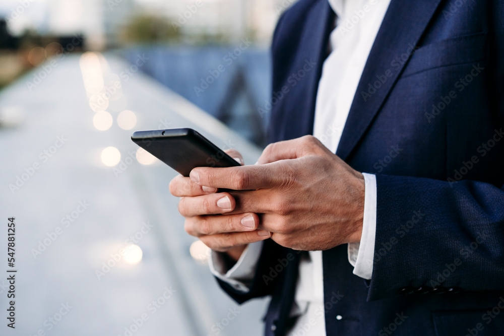 Hands of businessman text messaging through smart phone Hands of businessman text messaging through smart phone