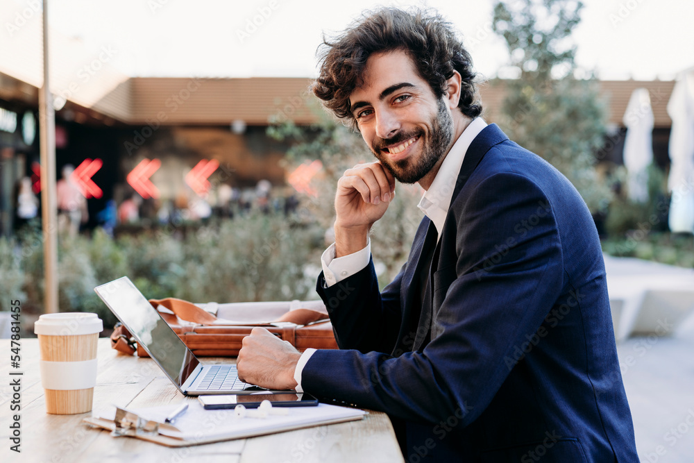 Handsome businessman with laptop at table working from cafe Handsome businessman with laptop at table working from cafe