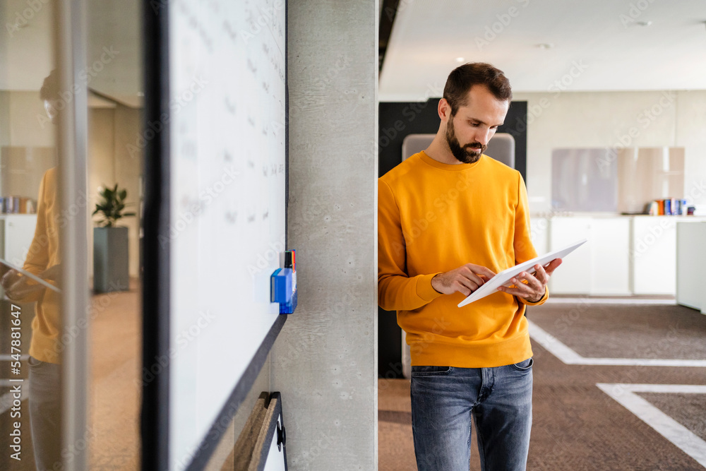 Businessman using tablet PC leaning on wall at office Businessman using tablet PC leaning on wall at office