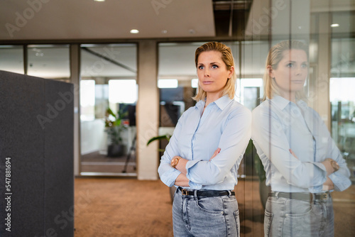 Wallpaper Mural Contemplative businesswoman with arms crossed standing near glass wall Torontodigital.ca