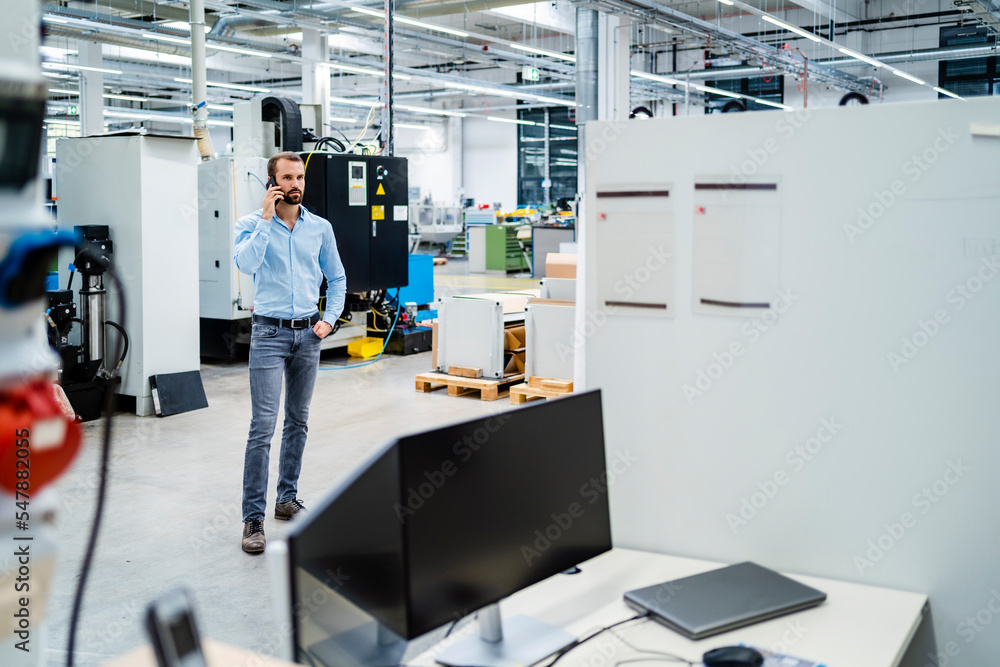 Businessman talking on smart phone standing in factory Businessman talking on smart phone standing in factory