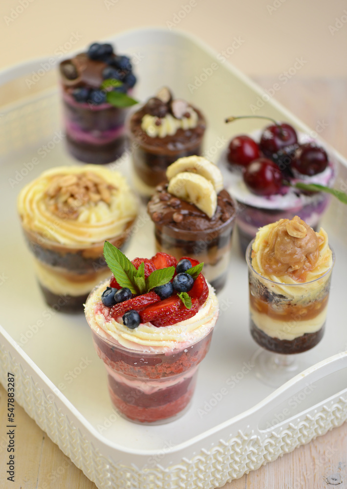 Homemade desserts in glass jars. Traditional unbaked Italian dessert on a white background. Cake with coffee, berries, fruits and mascarpone cream. Homemade desserts in glass jars. Traditional unbaked Italian dessert on a white background. Cake with coffee, berries, fruits and mascarpone cream.