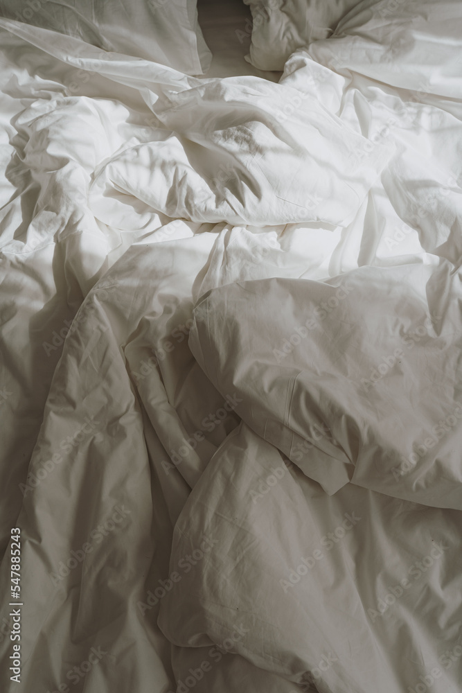 Comfortable white crumpled bed linens with sunlight shadows reflections. Morning in bed concept - obrazy, fototapety, plakaty 