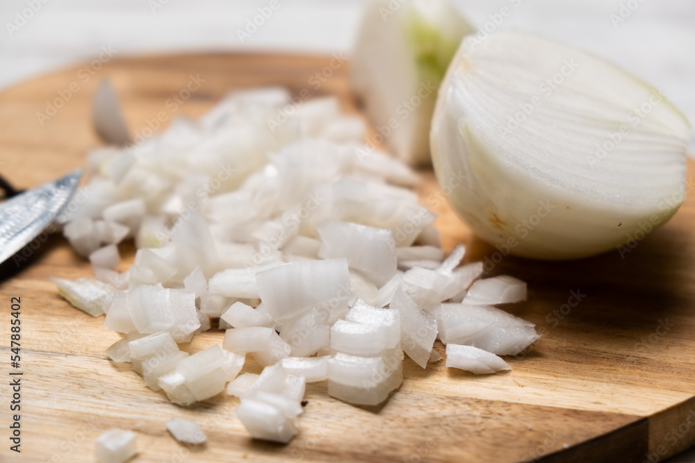 Diced onion on a wooden cutting board. Sliced white onion. Diced onion on a wooden cutting board. Sliced white onion.
