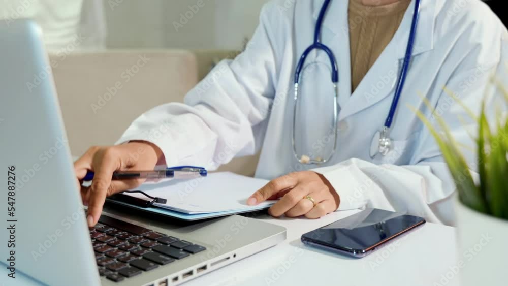Doctor or nurse in uniform with stethoscope writing something information of patient in paperwork checklist on clipboard and typing the information of patients to laptop computer, prescription medical Doctor or nurse in uniform with stethoscope writing something information of patient in paperwork checklist on clipboard and typing the information of patients to laptop computer, prescription medical