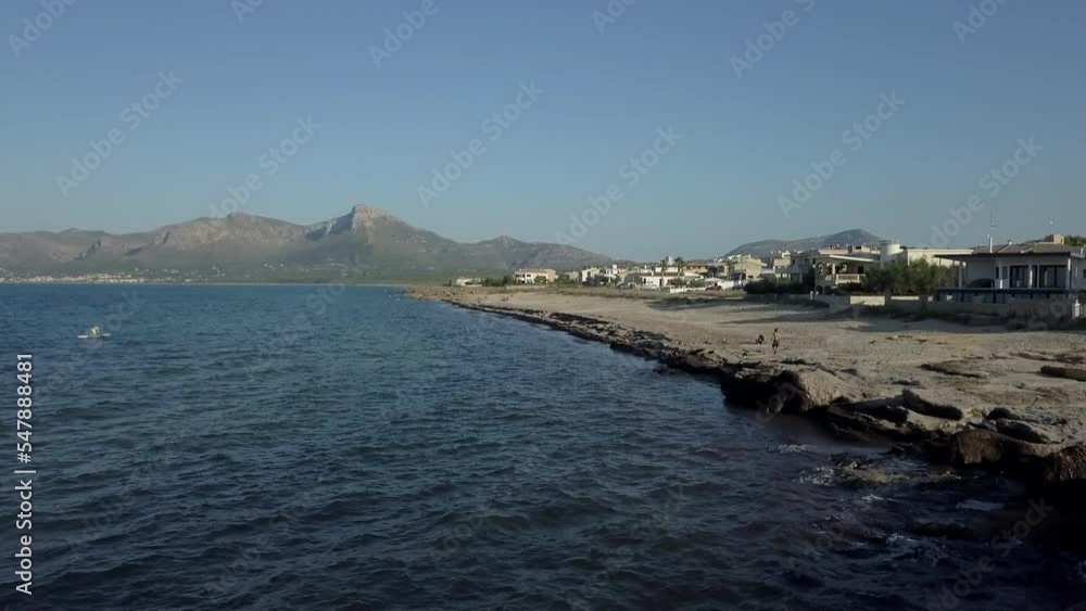 Aerial view of sea water and people in the distance with a village next to it Aerial view of sea water and people in the distance with a village next to it