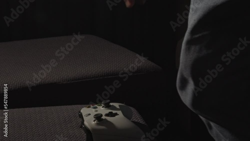 Male Hands playing with a videogame controller and putting it down and man standing up in a dark living room