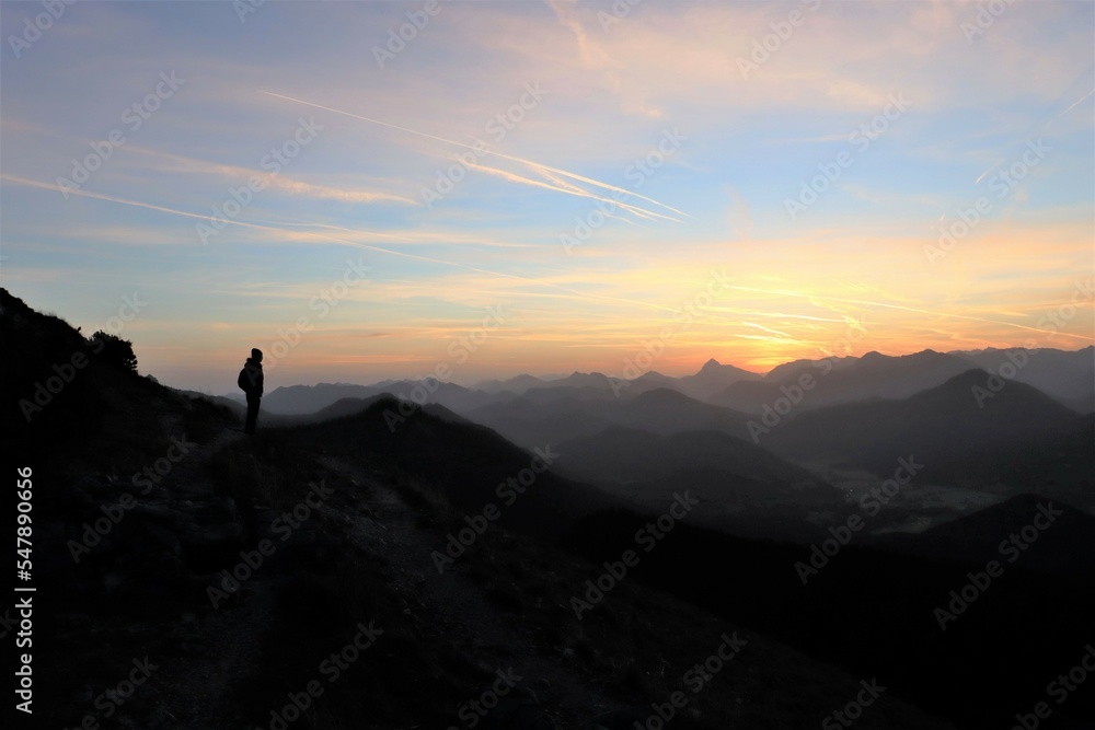 young hiker is standing on a mountain and watching the sunrise 