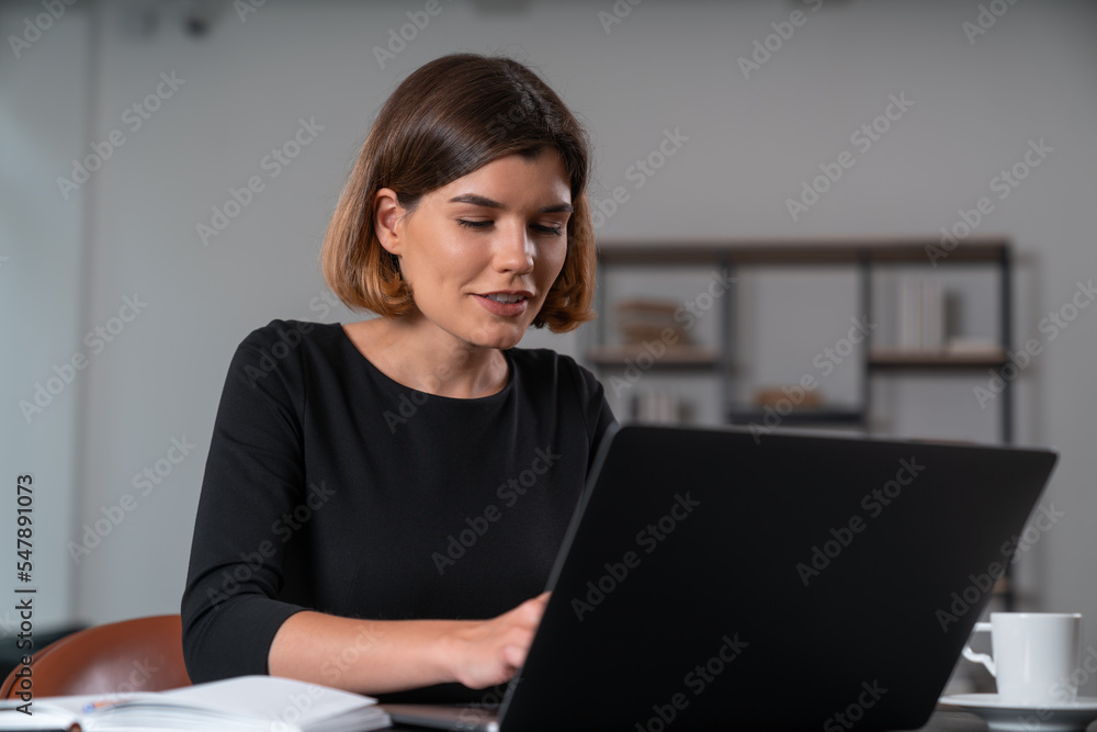 Satisfied attractive businesswoman in formal wear typing on laptop Satisfied attractive businesswoman in formal wear typing on laptop