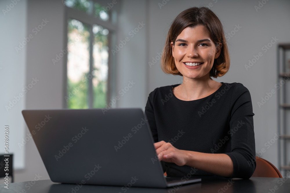 Smiling attractive businesswoman in formal wear typing on laptop Smiling attractive businesswoman in formal wear typing on laptop