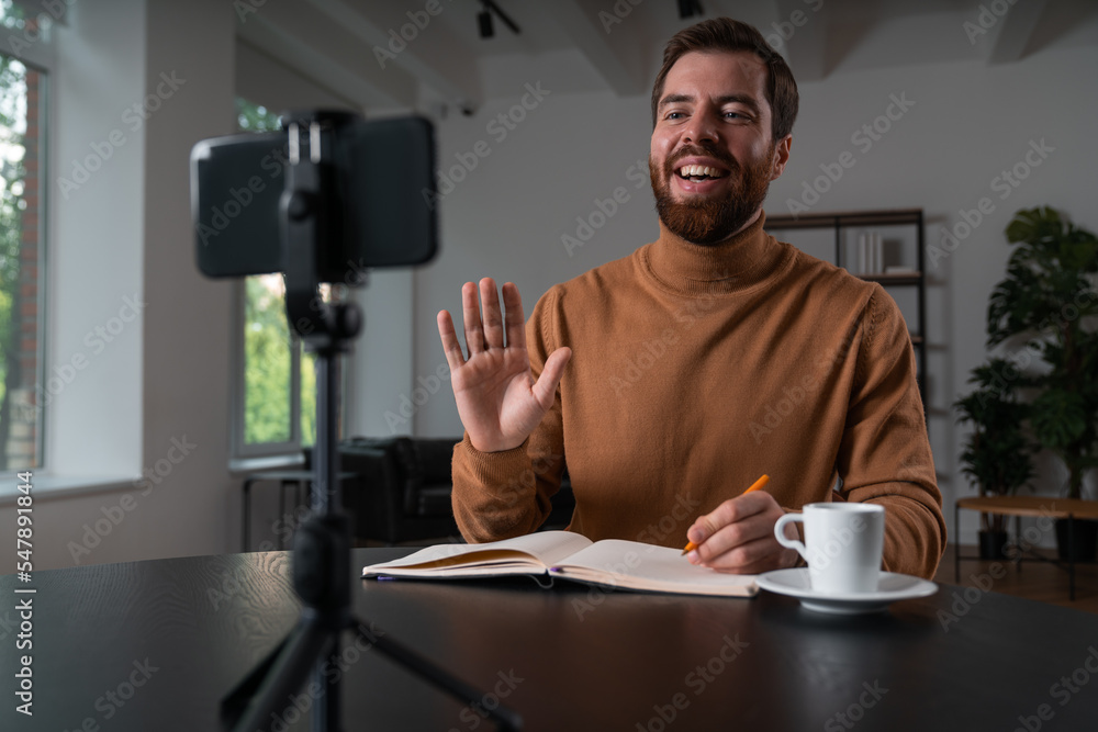 Cheerful businessman in casual wear is making video blog greeting Cheerful businessman in casual wear is making video blog greeting