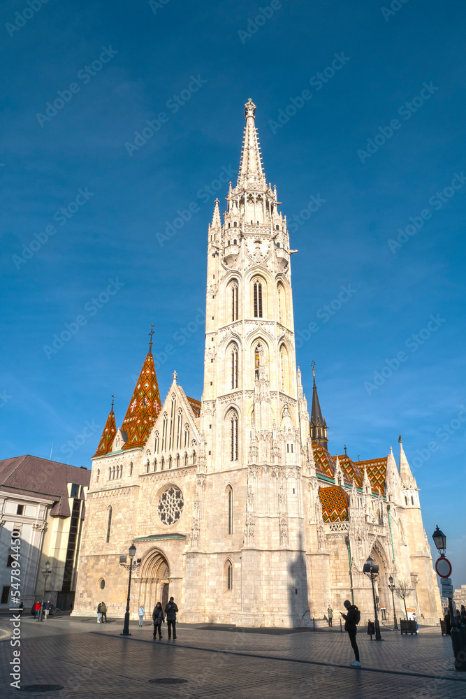 Facade with tower of Matthias Church or The Church of the Assumption of the Buda Castle during sunny day with blue sky in Budapest