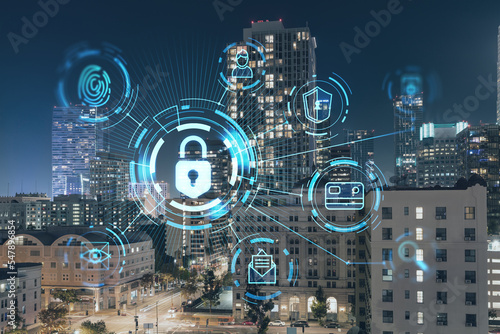 Illuminated cityscape of Los Angeles downtown at night, California, USA. Skyscrapers of LA city. Glowing Padlock hologram. The concept of cyber security to protect companies confidential information