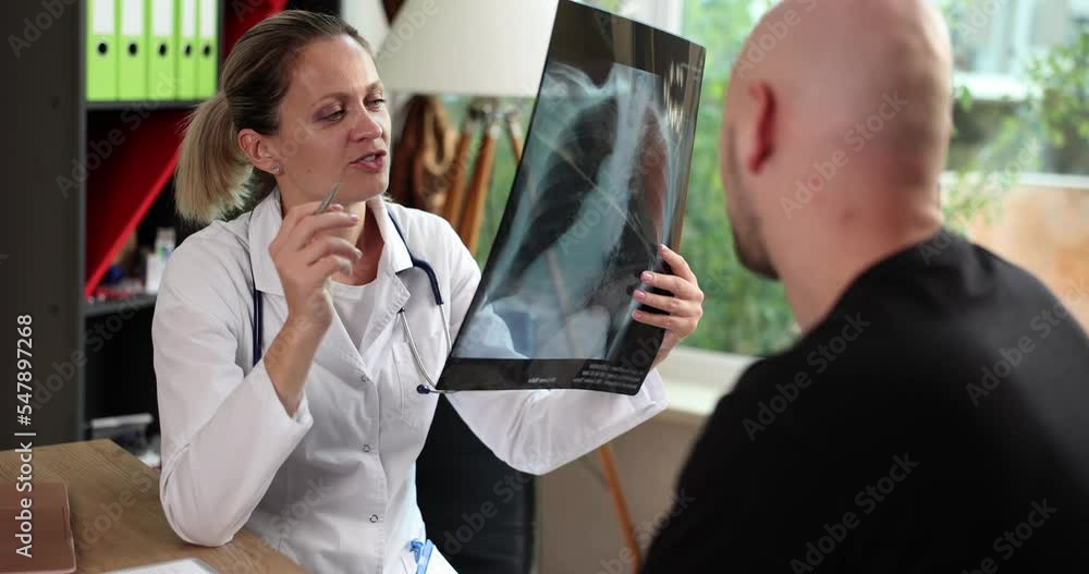 Female doctor in explaining diagnosis on x-ray lung fluorography to male patient during medical appointment in hospital Female doctor in explaining diagnosis on x-ray lung fluorography to male patient during medical appointment in hospital