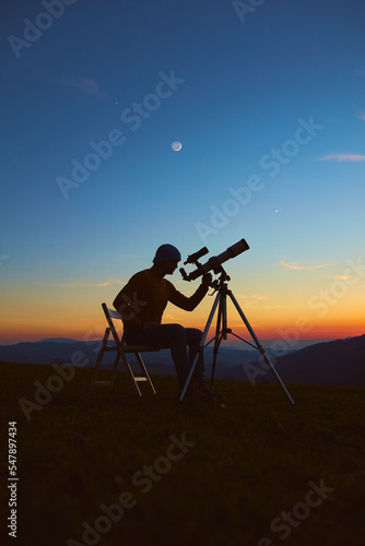 Man with astronomy telescope looking at the night sky, stars, planets, Moon and shooting stars.