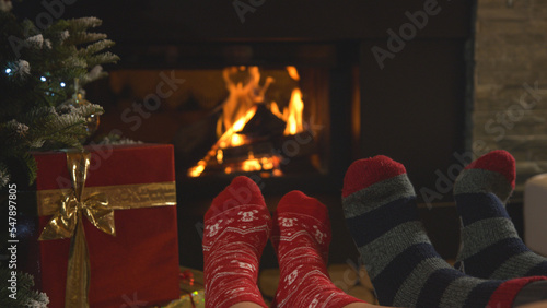 CLOSE UP: Couple rest by fireplace and warming up their feet in Christmas socks