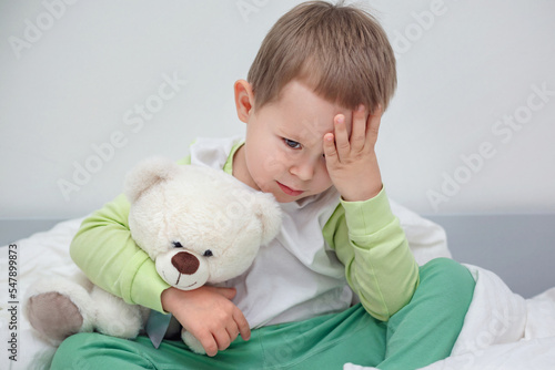 the child is sad, boy 3 years old upset and hugging his teddy bear