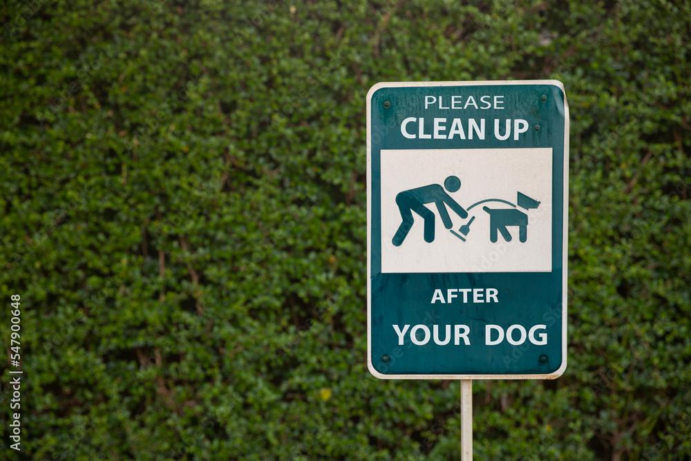 Clean Up After Your Dog sign against green grass in park . Clean Up After Your Dog sign against green grass in park .