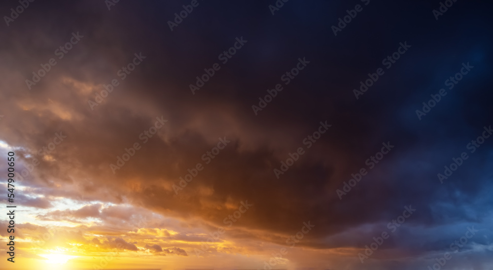 A autumn sunset sky with orange and dark stormy clouds as a background or texture