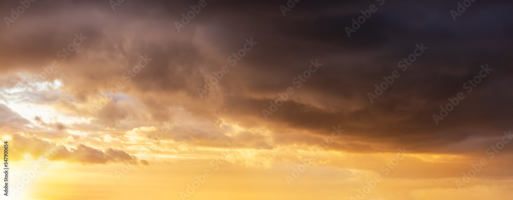 Panorama of a autumn sunset sky with orange and dark stormy clouds as a background or texture