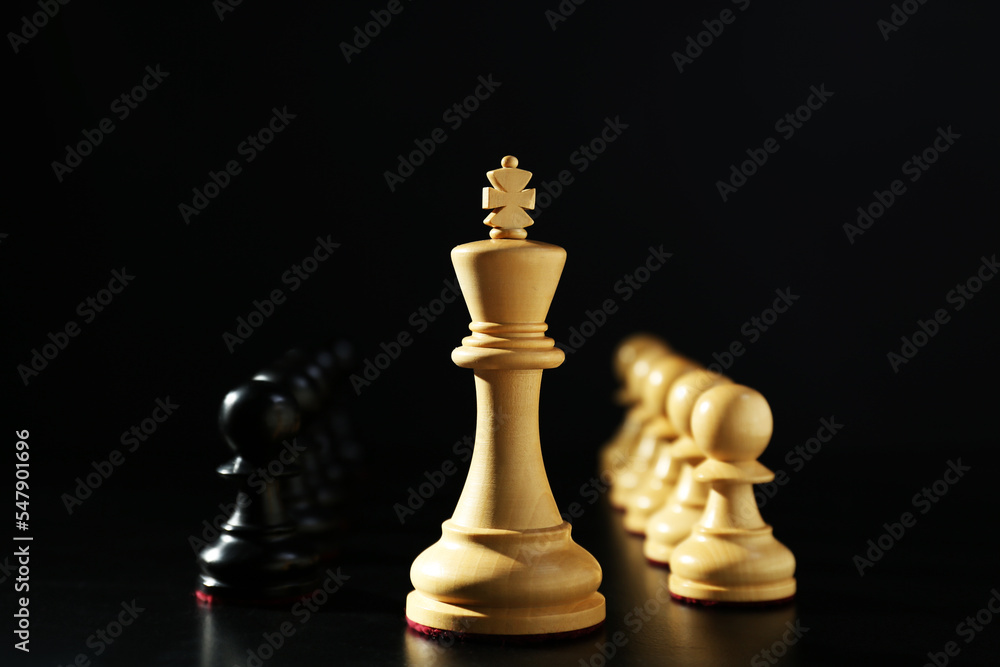 Wooden king, white and black chess pieces against dark background. Competition concept Wooden king, white and black chess pieces against dark background. Competition concept