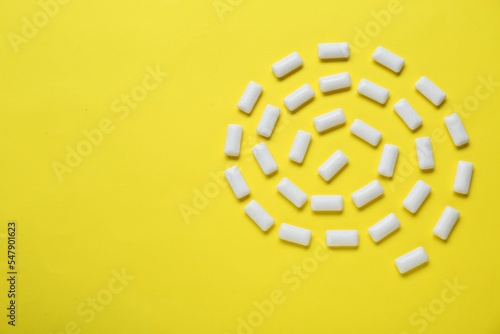 Tasty white chewing gums on yellow background, flat lay. Space for text photo