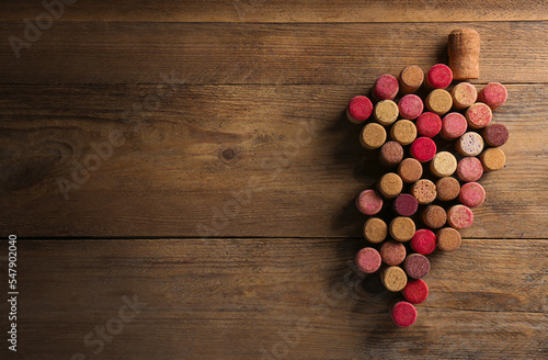 Grape made of wine bottle corks on wooden table, top view. Space for text