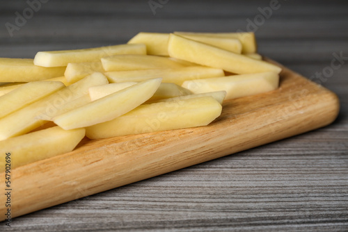 Cut raw potatoes on wooden table, closeup