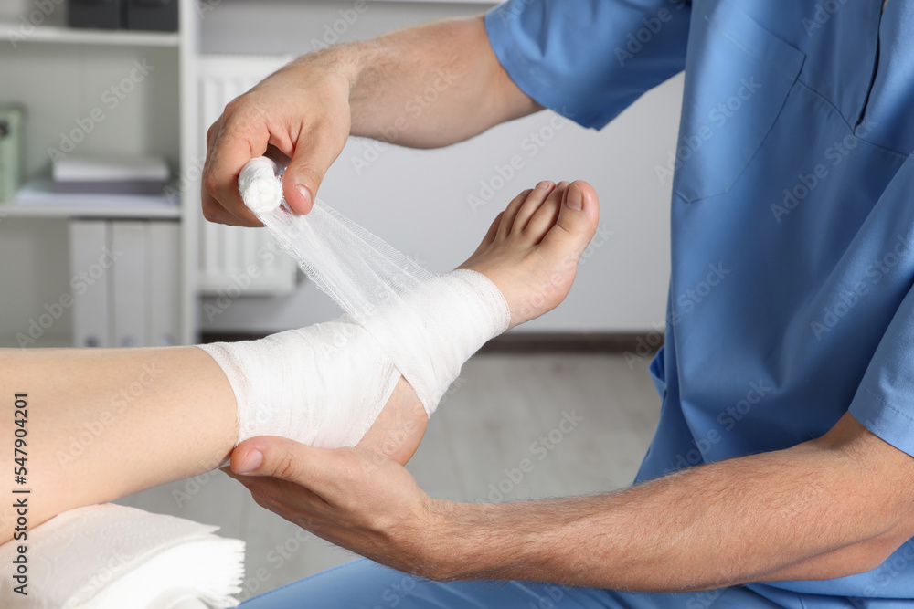 Doctor applying bandage onto patient's foot in hospital, closeup Doctor applying bandage onto patient's foot in hospital, closeup