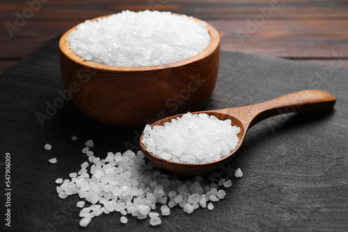Spoon and bowl of natural sea salt on wooden table
