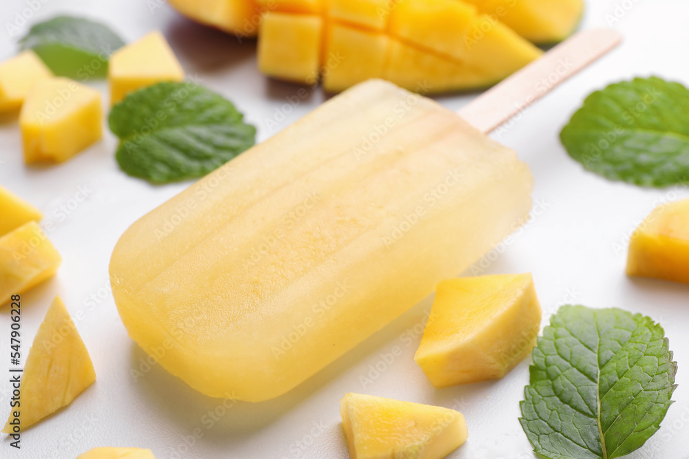 Tasty mango ice pop on white table, closeup. Fruit popsicle Tasty mango ice pop on white table, closeup. Fruit popsicle